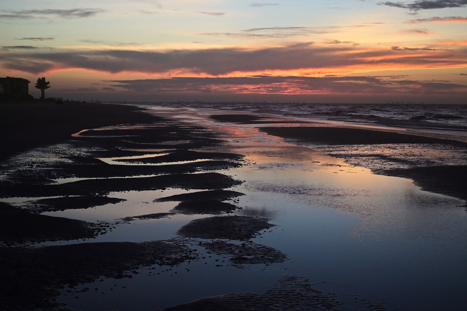 Sunset over tidal pools on a Sanibel beach, the hour when tables fill at the best Sanibel Island restaurants
