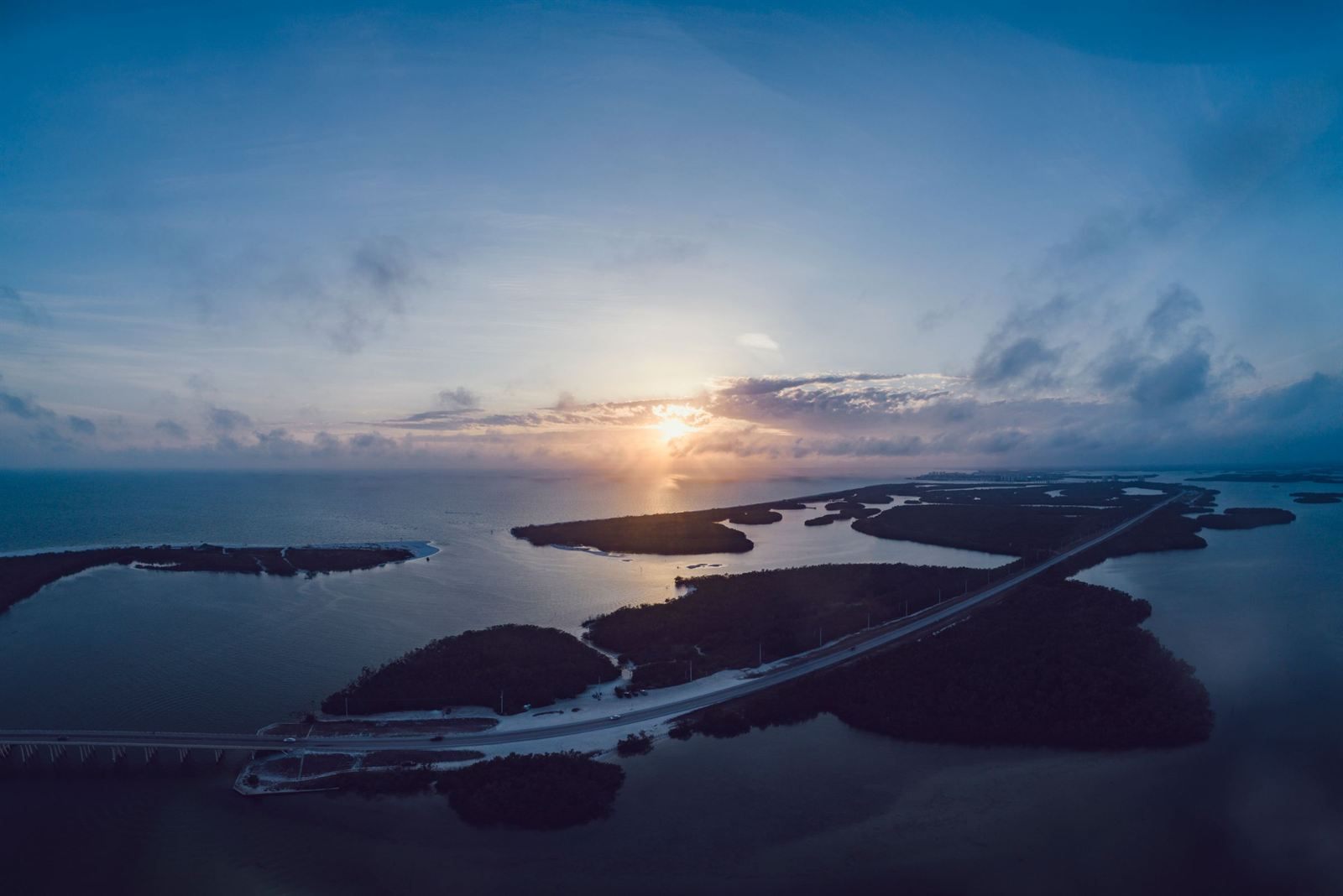 A causeway road crossing small islands in the bay near Fort Myers at sunset